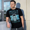 This image shows a young man standing on top of a parking deck near the elevator. He is leaning against the wall while sun illuminates the Shin Megami Tensei III Demi Fiend shirt by Eighty Sixed.