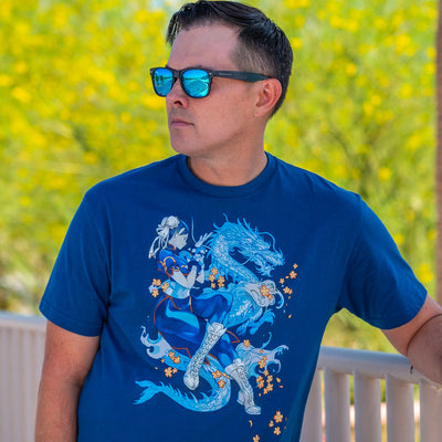 Photo of a man wearing the Street Fighter Chun Li shirt. He's wearing blue tinted sunglasses, with a nice blurred background of yellow flowers.
