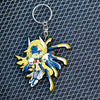 Image showcasing the Mu-12 keychain from the Blazblue merchandise collection, positioned against a backdrop featuring a cool metal grate.