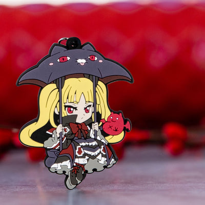 Image showcasing the Rachel keychain, a piece of Blazblue merchandise, set against a vibrant red background adorned with red flower buds.