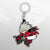 Image showcasing the Ragna keychain, a piece of Blazblue merchandise, set against a pixelated background.