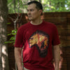 This image is of a young man wearing the Expedition Monster Hunter shirt. He is in a forest with a rusty metal wall behind him, he is staring intently in the other direction away from the camera.