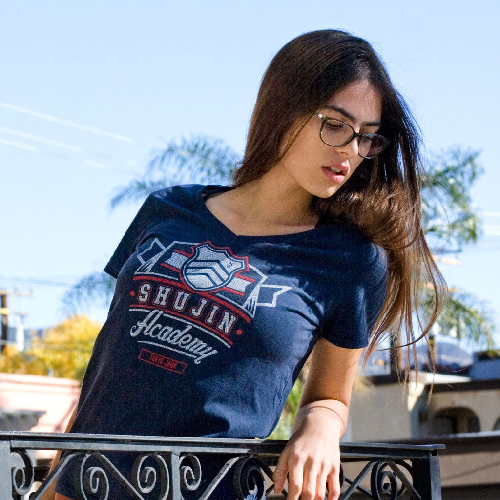 a beautiful young woman looks over a city balcony down at the crowd below. She is wearing the Shujin Academy Persona 5 shirt by Eighty Sixed.