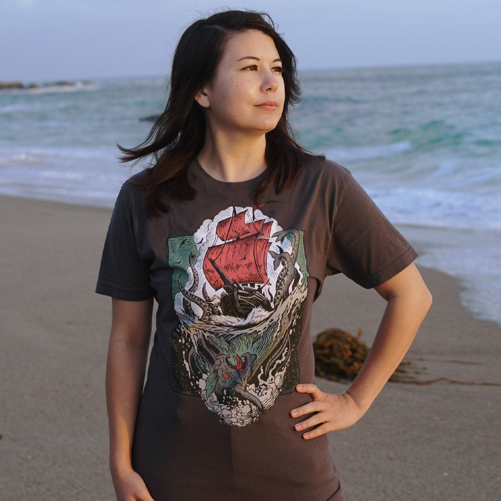 Woman at the beach wearing the Sea of Thieves Kraken T-Shirt with ocean backdrop