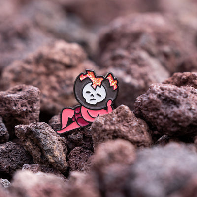 The Shin Megami Tensei V Lazy Miman pin is shown on a bed of red volcanic rock, looking like he is relaxing.