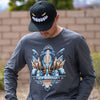 Photo of a man wearing the Skullgirls New Meridian long sleeve. He is also wearing the Skullgirls Samson hat, there is a nice blurred background of trees.