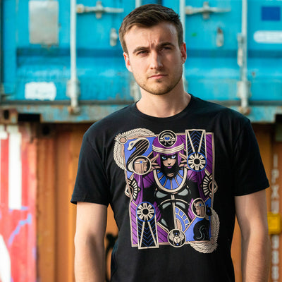 Photo of a man wearing the Street Fighter Menat tee. In the background are different colored shipping containers that are nicely blurred for a subtle bokeh effect.