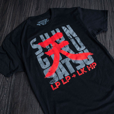 A nice flat lay photograph of the Shun Goku Satsu shirt. It is sitting on a wood grain table that is stained in black.