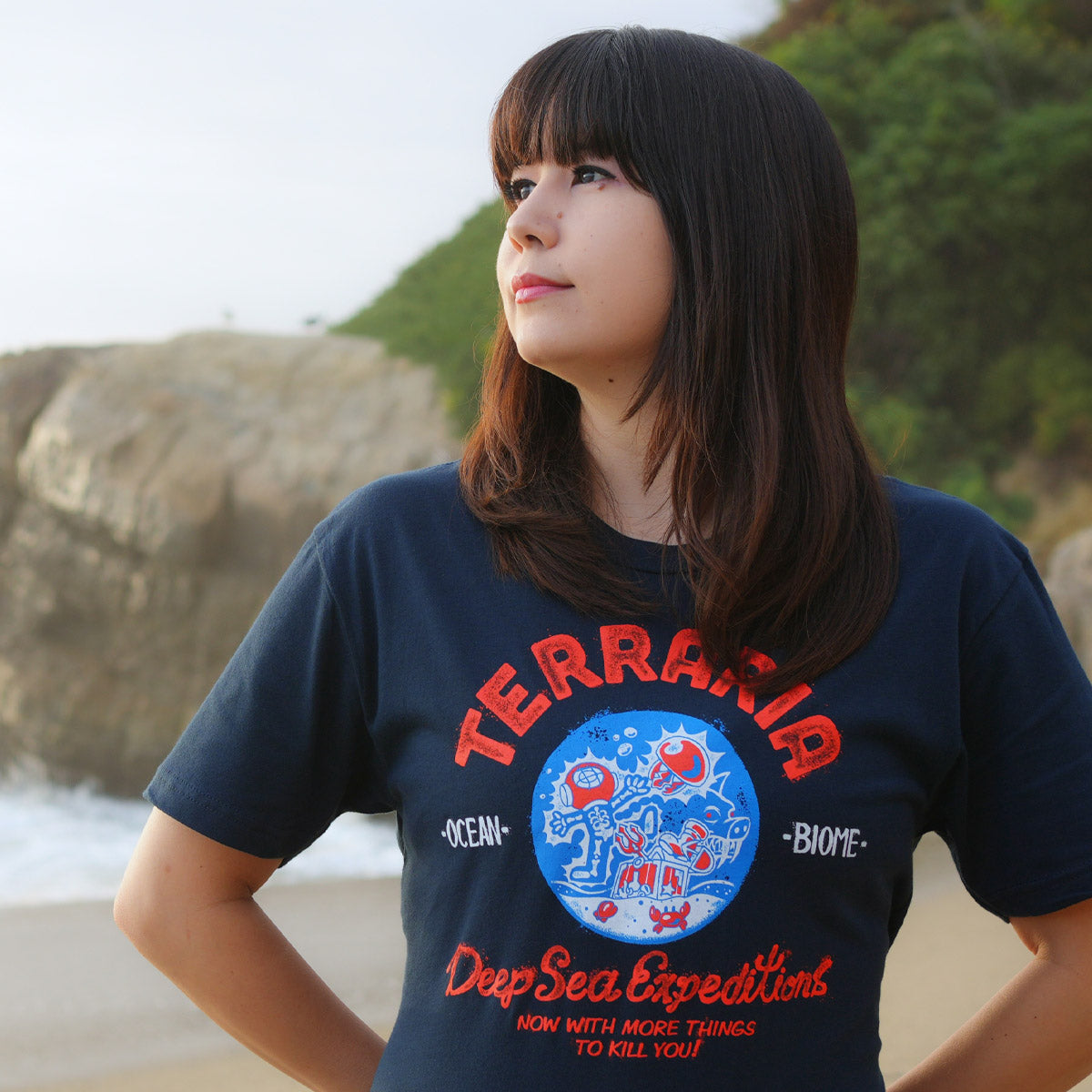 Close up of the model wearing the Terraria Ocean Biome t-shirt - Dark navy t-shirt with red orange print. 