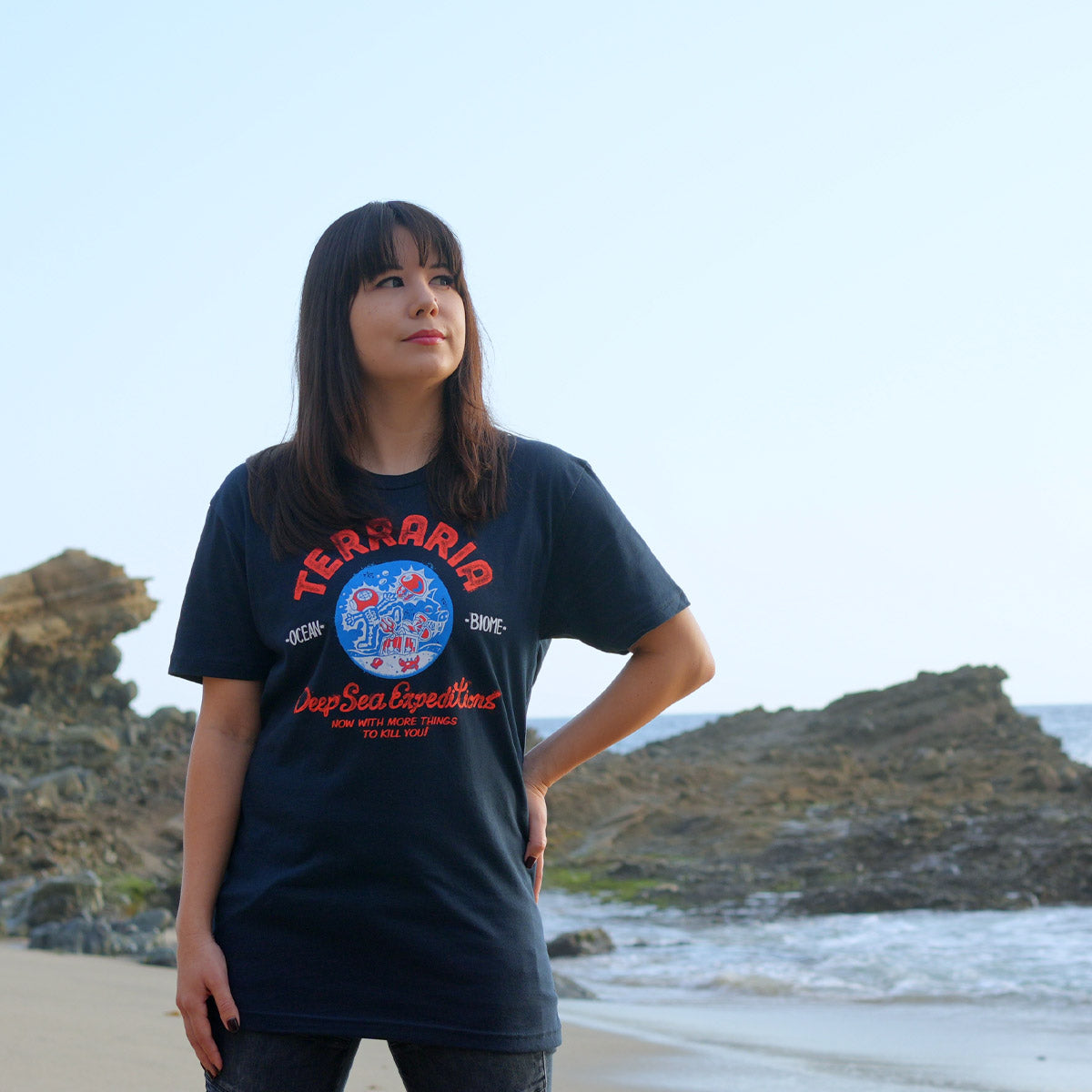 Model wearing the dark navy Terraria Ocean Biome t-shirt at the beach. 